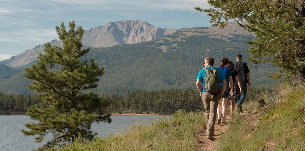 Hikers travel in front of Pikes Peak using local hiking tips.