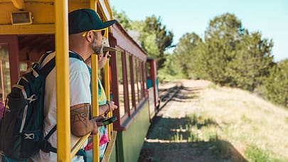 A man rides the open-air car of the Cripple Creek Railroad.