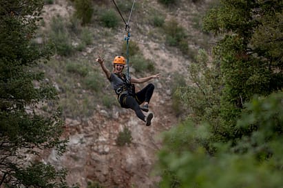 Cute girl in dress and shorts hanging up side down at a climbing