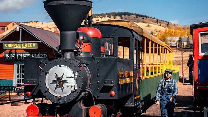 A train conductor walks alongside the Cripple Creek and Victor Narrow Gauge Railroad at the train depot.