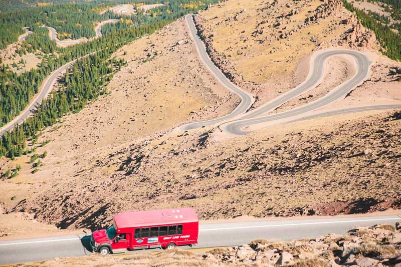 Pikes Peak tour by Gray Line Red Bus driving up the highway.