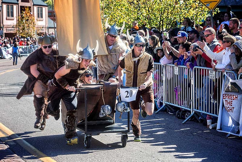 A coffin on wheels with a Viking rider and several Vikings pushing it in the Emma Crawford coffin race.