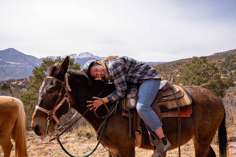 Woman hugging horse with Pikes Peak in the background
