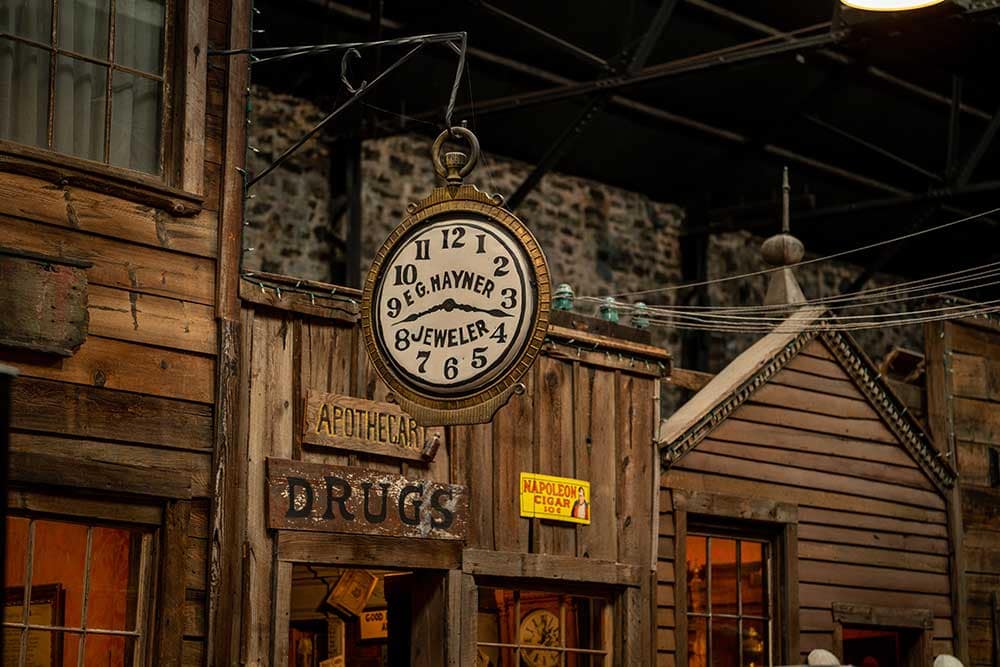 A large outdoor clock hangs over the board walk at Ghost Town Museum.