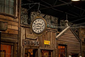 A large outdoor clock hangs over the board walk at Ghost Town Museum.
