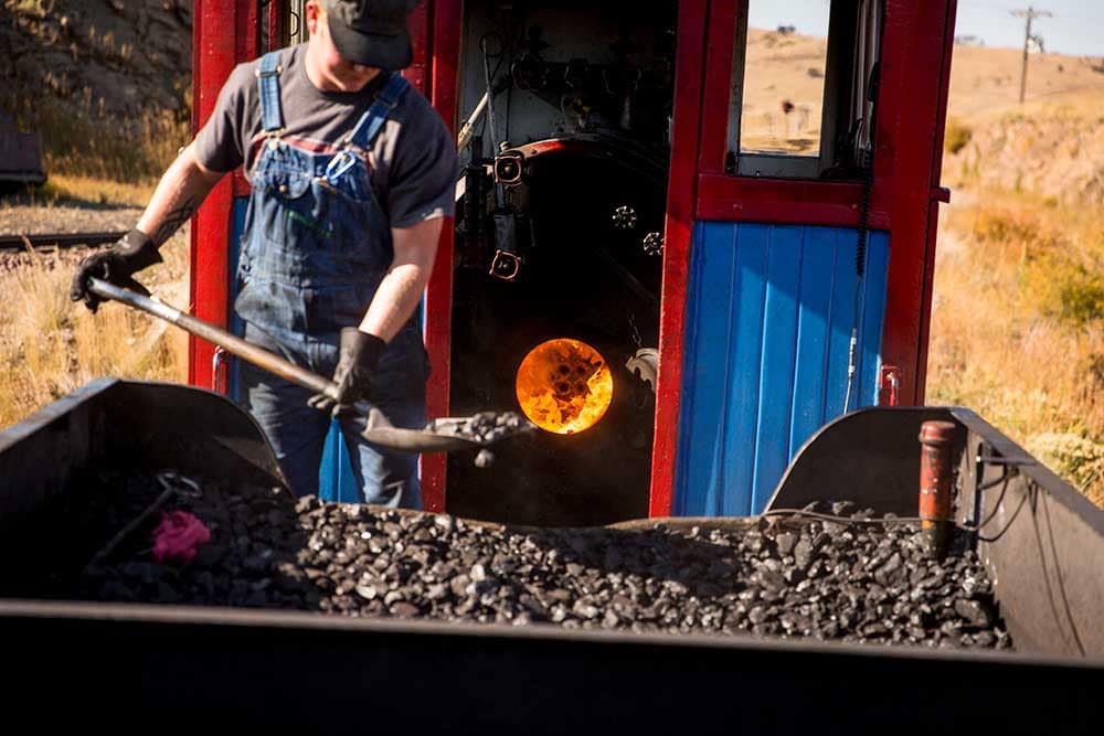 Cripple Creek and Victor Narrow Gauge Railroad Conductor shoveling coal to fuel train.