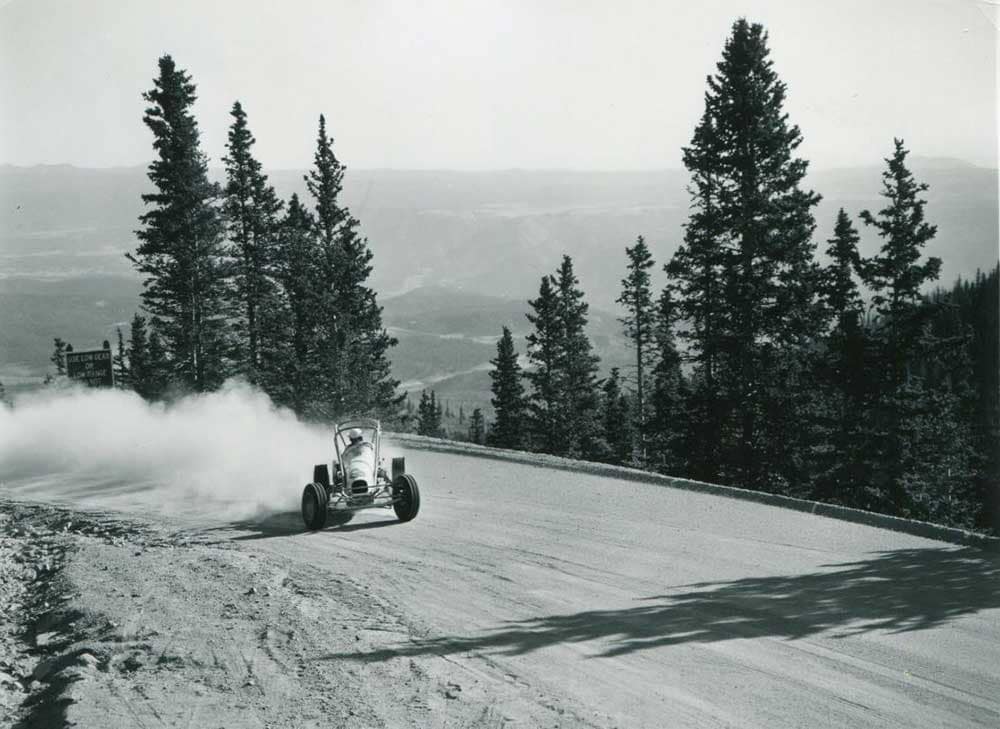 A race car leaves a trail of dust during the early days of the Race to the Clouds.