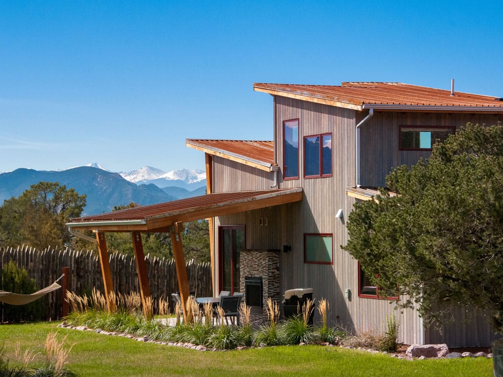 A large, two story Royal Gorge cabin with mountains in the background.