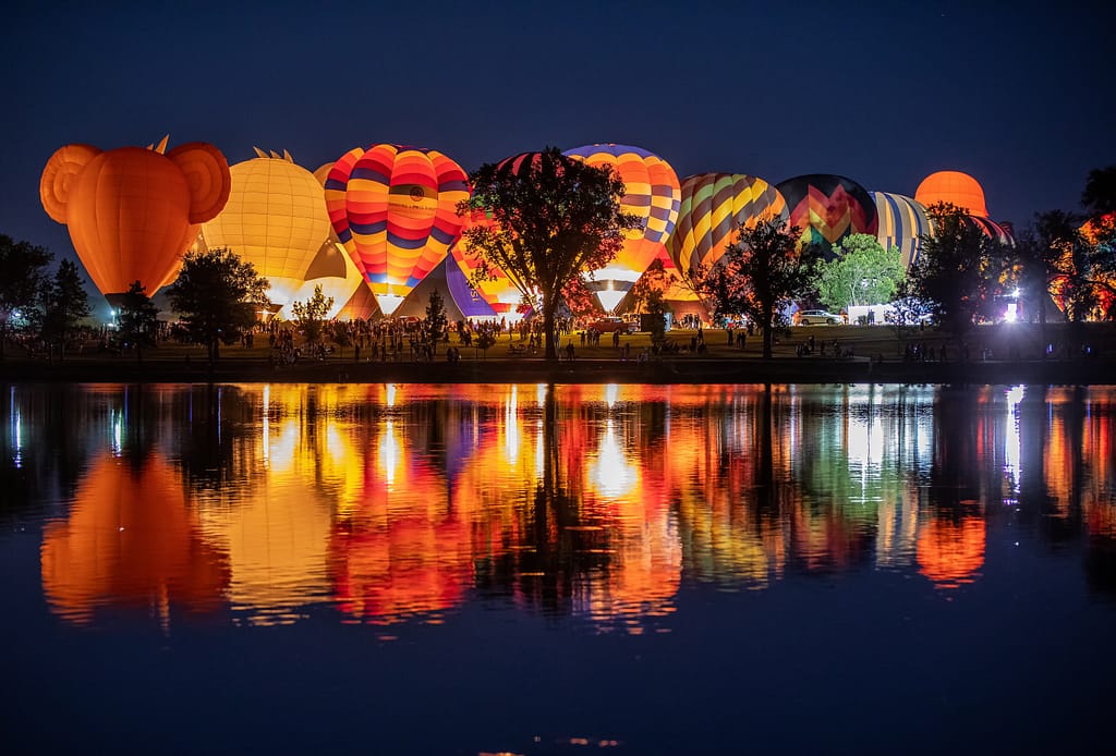 Hot air balloons glowing at night over Prospect Lake during Labor Day Liftoff in Colorado Springs