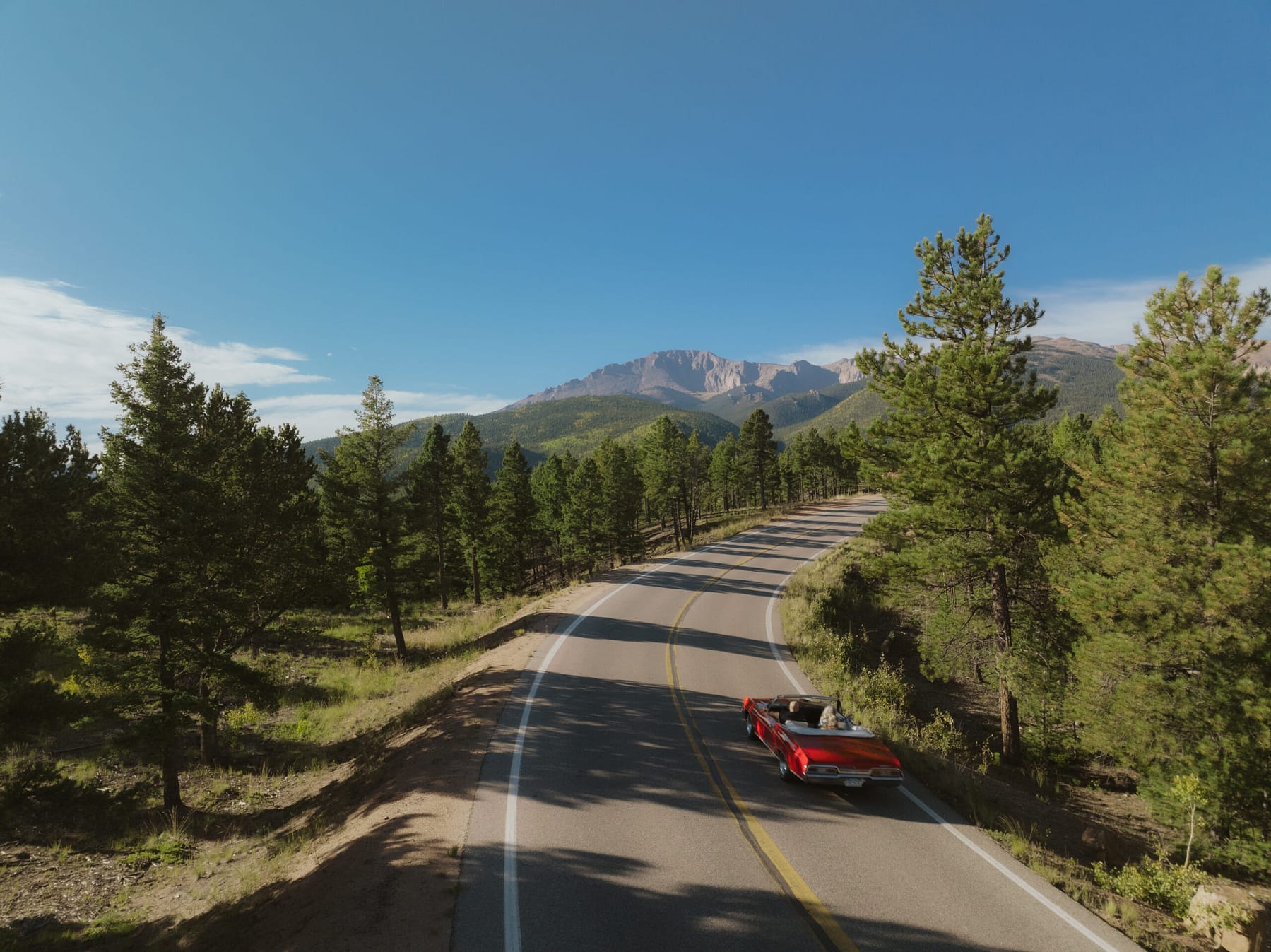 Un viejo coche rojo subiendo por la carretera de Pikes Peak