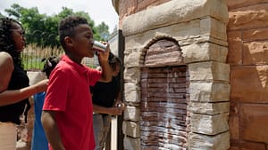 Young boy at mineral spring drinking out of a cup.