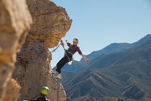 Woman hanging off cliff at Cave of the Winds Via Ferrata