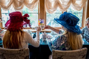 Women in fancy hats clinking tea cups at Miramont Castle