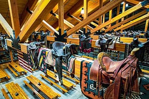 Saddles and blankets perch on beams in the Flying W Ranch Old West Collection.