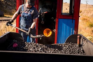 Cripple Creek and Victor Narrow Gauge Railroad Conductor shoveling coal to fuel train.