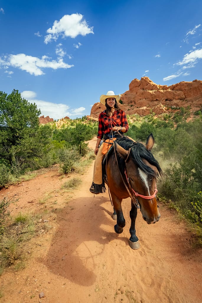 Cowgirl riding horse through Garden of the Gods with Academy Riding Stables